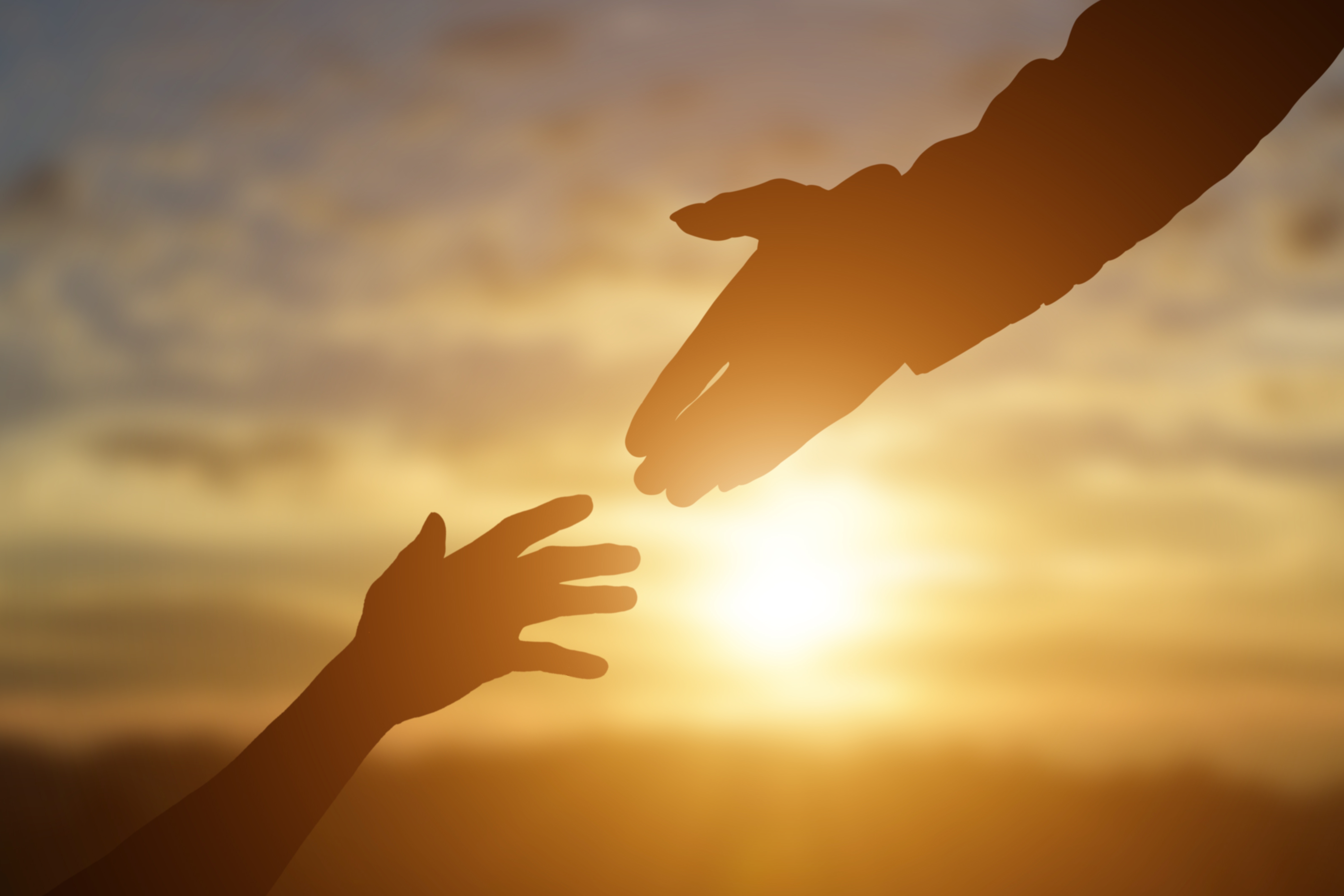 Silhouette of giving a help hand, hope and support each other over sunset